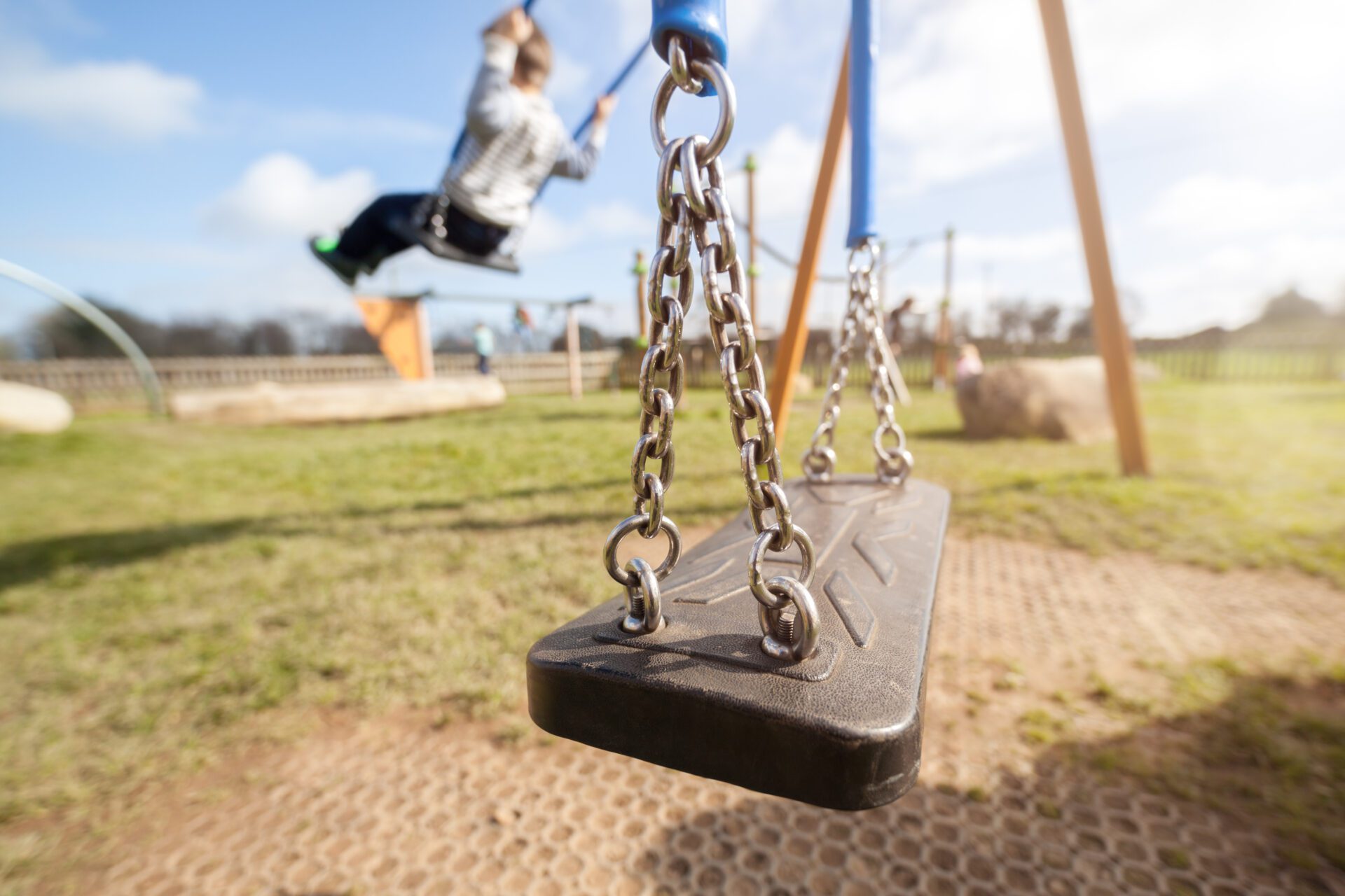 Playground swing with children playing in the background